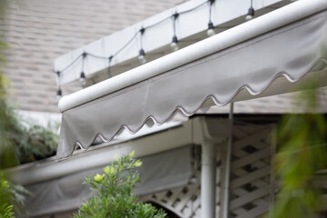 Poster - A white awning with a grey stripe is hanging over a house