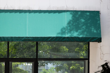 Wall Mural - A green awning is above a window with a view of trees