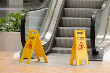 Wall Mural - Two yellow caution signs are placed on the steps of an escalator