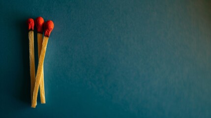 Three red-tipped matches stand against a teal background