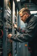 © Fotograf - A person is sitting at a desk with a computer, surrounded by servers and network equipment