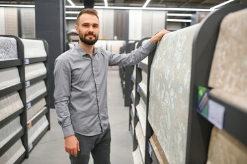 Wall Mural - a man chooses wallpaper for pasting walls in a hardware store