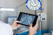 © natali_mis - A doctor examines an X-ray on a tablet in a room .