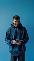 young man in blue hoodie happily using smartphone for communication