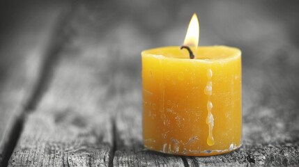 Wall Mural -   Close-up shot of a yellow candle on a wooden table with droplets of water on its surface