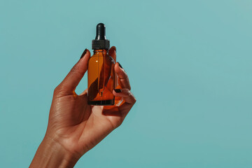 Wall Mural - amber dropper bottle in hand against turquoise backdrop, ideal for beauty and wellness product image