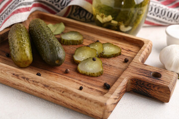 Wall Mural - Wooden board with tasty canned cucumbers on white background