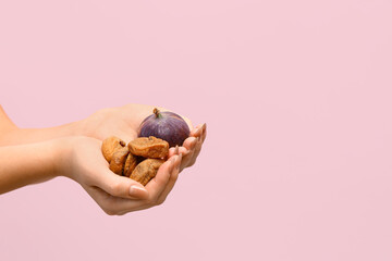 Wall Mural - Female hands with tasty dried and fresh figs on pink background