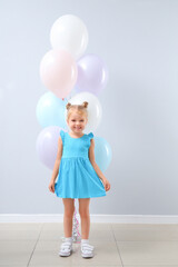 Wall Mural - Cute little girl with beautiful balloons near grey wall