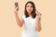 © Pixel-Shot - Young woman with mobile phone video chatting on beige background. Online dating concept