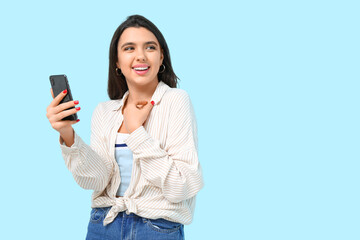 Wall Mural - Young woman with mobile phone on blue background. Online dating concept