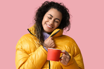 Sticker - Happy young African-American woman with cup of hot mulled wine on pink background