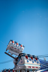 Wall Mural - People enjoying a thrilling ride at an amusement park, captured against a clear blue sky