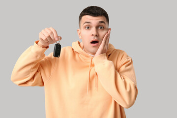 Poster - Shocked young man with car key on grey background