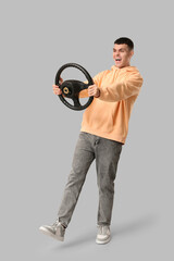 Poster - Emotional young man with steering wheel on grey background