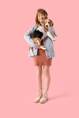 Wall Mural - Young woman in casual attire holding cute beagle dog on pink background