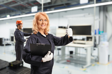 Wall Mural - Female factory worker in a uniform and helmet posing in a factory