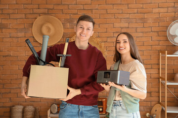 Canvas Print - Young couple with box of unwanted stuff in room. Yard Sale