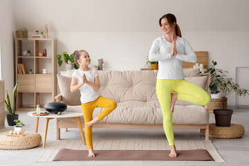 Poster - Young woman with her little daughter doing yoga on mat at home