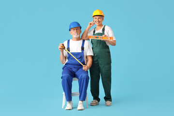 Poster - Mature couple of decorators with tape measure and level on blue background