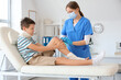 © Pixel-Shot - Injured little boy with bruised knee visiting doctor in clinic