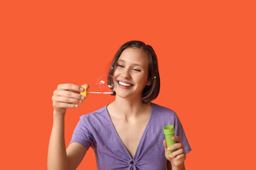 Wall Mural - Happy teenage girl with soap bubbles on orange background