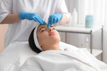 Sticker - Beautician removing woman's hair on face with wax strip in salon, closeup