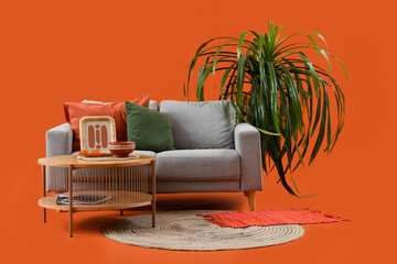 Wall Mural - Sofa with table and palm tree on orange background