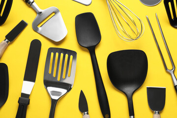 Wall Mural - Different spatulas and other kitchen utensils on yellow background, flat lay
