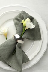 Wall Mural - Stylish setting with napkin, flowers and plates on light textured table, top view