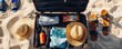 © Tin - Vacation suitcase on sandy beach with clothes, hats, sandals, and sunscreen. Ready for a summer holiday getaway under the sun.