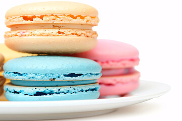 Poster - French macaron cookies in assorted colors on a white plate Stock Photo with copy space Isolated on white background