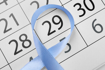 Wall Mural - International Psoriasis Day. Light blue ribbon and calendar page with marked date, top view