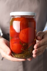 Wall Mural - Woman holding jar with tasty pickled tomatoes, closeup