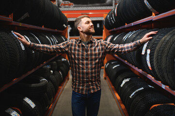 Male mechanic holding car tire in automobile store