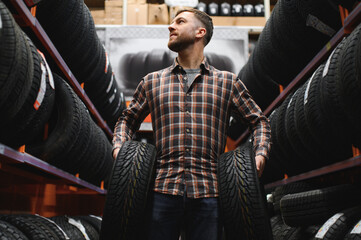 Wall Mural - Male mechanic with car tires in automobile service center