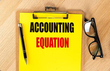 Poster - ACCOUNTING EQUATION text on yellow paper on clipboard with pen and glasses