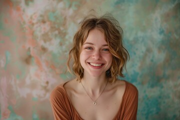 Wall Mural - Portrait of a blissful caucasian woman in her 20s smiling at the camera in front of pastel or soft colors background