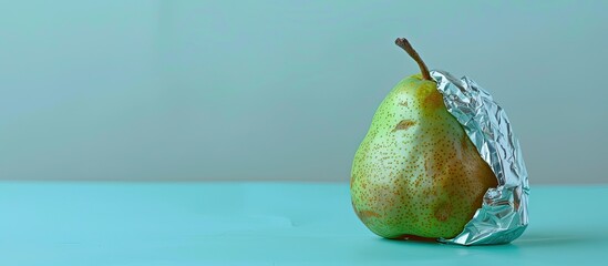 Poster - a pear covered with aluminum foil pastel background. with copy space image. Place for adding text or design