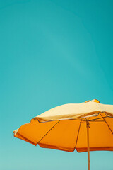 Wall Mural - bright yellow beach umbrella and cloudless clean sky, blue and red colors, minimalistic retro style wallpaper, travel poster background