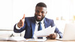 © Prostock-studio - Partnership concept. Cheerful african american businessman holding documents and extending hand to shake, office interior, copy space