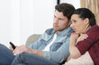 © auremar - sad couple at home sitting on sofa watching tv