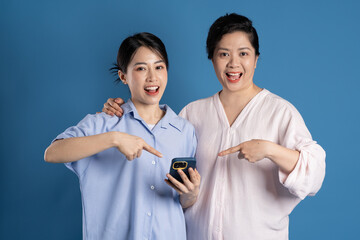 Wall Mural - Image of an Asian mother and child posing on a blue background.