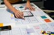 © NINENII - UX developer and ui designer brainstorming about mobile app interface wireframe design with customer breif and color code at office.