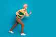 © deagreez - Full size photo of pretty retired female running hold copybooks wear trendy elegant outfit isolated on blue color background