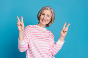 Poster - Photo portrait of lovely pensioner lady show v-sign dressed stylish striped garment isolated on blue color background