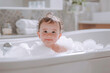 © Mikhail - A joyful baby smiling while sitting in a bathtub filled with bubbles in a bright bathroom. Captures childhood, happiness, and cleanliness