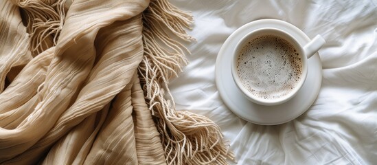 Wall Mural - Cup of hot coffee and warm scarf on white bed.Winter and cold weather concept. Copy space image. Place for adding text and design