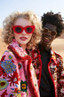 © Femmes.Digital - Fashionable couple in vibrant floral jackets and sunglasses posing in a desert landscape. The bold and trendy elements create a chic and modern aesthetic. Fashion photography concept.