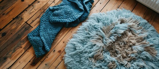 Poster - Overhead view of a fuzzy blue blanket above rug on wooden floor. Copy space image. Place for adding text and design